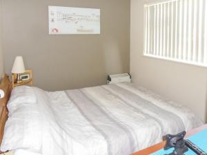 a bedroom with a white bed with a window at Hollyhocks in Walcott