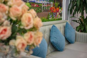 eine weiße Couch mit blauen Kissen und Blumen darauf in der Unterkunft Blau Hotel in Hanoi