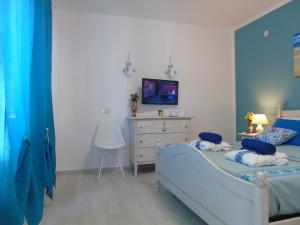 - une chambre avec un lit et une télévision murale dans l'établissement Affittacamere LiKele, à Castelsardo
