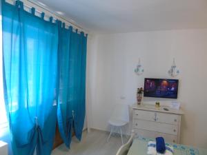 - une chambre avec des rideaux bleus, un lit et une commode dans l'établissement Affittacamere LiKele, à Castelsardo
