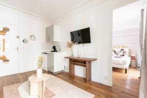 a white living room with a tv and a couch at Apartment next Tour Montparnasse - Sable in Paris