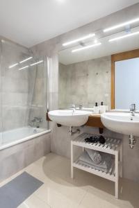 een badkamer met 2 wastafels, een bad en een spiegel bij Home2Book Cozy Apt Santa Úrsula, Sea Views & Pool in Santa Úrsula