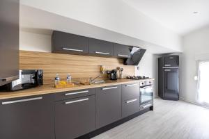 cocina con armarios grises y nevera negra en Le Solstice - Centre-Ville - Arrivée Autonome, en Annonay