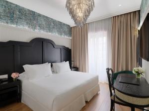 Un dormitorio con una cama grande, una mesa y una lámpara de araña. en H10 Corregidor Boutique Hotel, en Sevilla