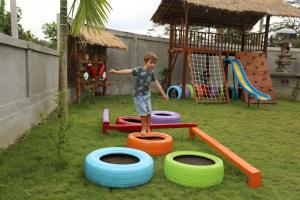 een jonge jongen speelt op een speelplaats met banden bij Kampung Uma Dawa Villas and Spa in Ubud