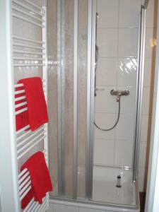 y baño con ducha y 2 toallas rojas. en Kleines Logierhaus 05, en Norderney