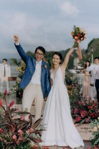 a bride and groom jumping in the air with their hands up at Indochine Cruise Lan Ha Bay Powered by ASTON in Ha Long