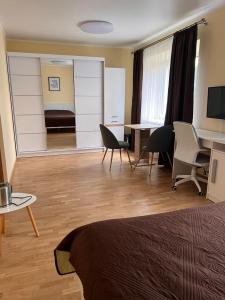 a room with a bed and a desk and chairs at Kepezinski ECO Apartments in Kaunas