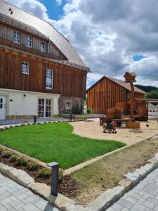 - un grand bâtiment en bois avec une cour devant dans l'établissement Lerchenberghof - barrierefreies Familien Landhotel mit FeWo, FeZi - Spielplatz Reiten Segway PT und mehr, à Kottmar