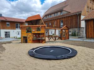 un grand trampoline dans le sable devant un bâtiment dans l'établissement Lerchenberghof - barrierefreies Familien Landhotel mit FeWo, FeZi - Spielplatz Reiten Segway PT und mehr, à Kottmar