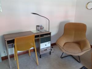 einen Schreibtisch mit einem Stuhl und einen Schreibtisch mit einer Lampe in der Unterkunft Le gîte blinois in Blain