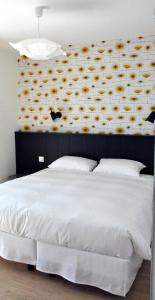 a bedroom with a large white bed with a flower wall at Logis Hotel Du Port in Plobannalec-Lesconil