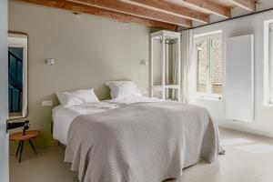ein weißes Schlafzimmer mit einem großen Bett und einem Fenster in der Unterkunft Posthuis in De Panne