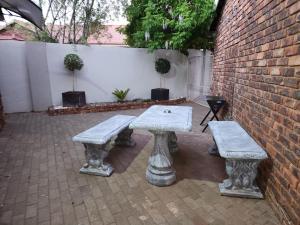 a picnic table and two benches next to a brick wall at The Honeycomb in Kimberley