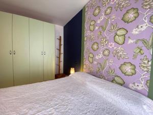 1 dormitorio con 1 cama con pared morada en Appartamenti di Andrea, en Valeggio sul Mincio