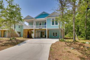 a blue house with a porch and a driveway at Coastal North Carolina Retreat - Walk to Beach! in Oak Island