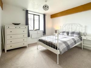 a white bedroom with a bed and a dresser at Coronation Mill Apartment in Mow Cop