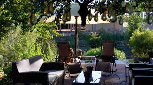 un patio con sillas, mesas y una sombrilla en Cunningham Cottage Guest House en Kuruman