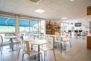 a dining room with tables and chairs and windows at Kyriad Direct Bordeaux Sud Cestas in Cestas