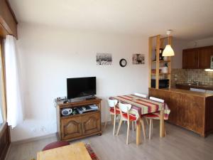 a living room with a table with a television and a kitchen at Appartement Auris, 1 pièce, 4 personnes - FR-1-297-331 in Auris