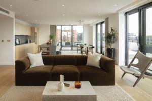 - un salon avec un canapé brun et une table dans l'établissement Modern Apartments at Enclave located in Central London, à Londres