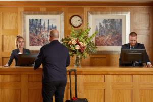 mężczyzna i kobieta siedzący przy biurku w obiekcie Macdonald Cardrona Hotel, Golf & Spa w mieście Peebles