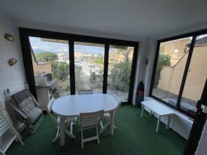 Pokój ze stołem, krzesłami i oknami w obiekcie T3 calme avec terrasse, clim et parking proche plage - FR-1-106-45 w mieście Saint-Cyprien