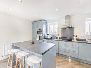 eine Küche mit weißen Schränken und einer großen Insel mit Hockern in der Unterkunft The Neal's 4 Bedroom House in Buxton Sleeps 8 in Buxton