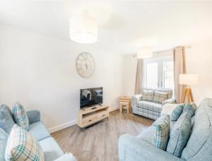 ein Wohnzimmer mit 2 blauen Sofas und einem TV in der Unterkunft The Neal's 4 Bedroom House in Buxton Sleeps 8 in Buxton