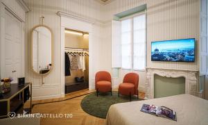 a bedroom with a bed and two chairs and a mirror at Albergo Diffuso Birkin Castello in Cagliari