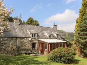 an old stone house with a conservatory in a garden at Gilfachwydd in Dolgellau