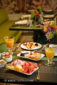 a table with plates of food and glasses of orange juice at Albergo Diffuso Birkin Castello in Cagliari