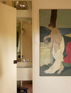 uma casa de banho com uma pintura de uma mulher ao lado de um lavatório em Casa Josephine Riofrío - retiro a 1 h de Madrid em La Losa
