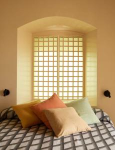 uma cama com almofadas em frente a uma janela em Casa Josephine Riofrío - retiro a 1 h de Madrid em La Losa