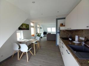 a kitchen with white cabinets and a table and chairs at Ferienwohnung Mack 1 in Wernigerode