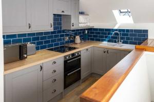 a kitchen with white cabinets and blue tiles at Stroan in New Galloway