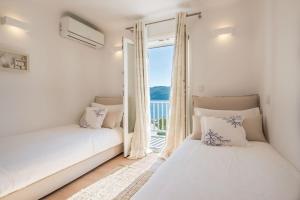 dwa łóżka w pokoju z oknem w obiekcie Villa Island , Luxury Villa in Mykonos w mieście Agia Anna