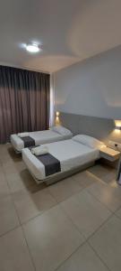 two beds in a room with two lamps at La Veranda Hotel in Larnaca