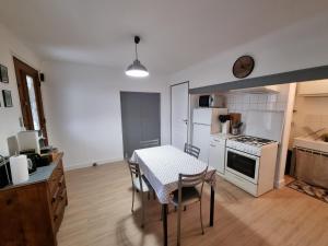 a kitchen with a table and chairs and a kitchen with white appliances at Maison avec extérieur dans un village provençal in Saint-Romain-en-Viennois