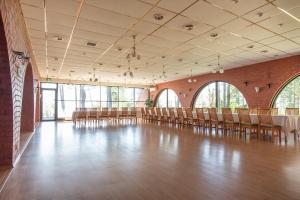un salón de banquetes con sillas, mesas y ventanas en Villa Andropoff, en Pärnu