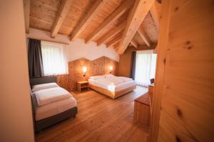 a bedroom with two beds and wooden floors and windows at Garnì Tuttotondo in Levico Terme