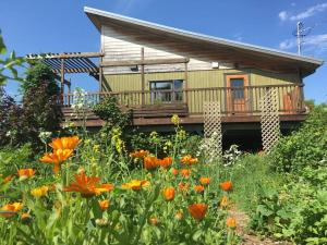 a house with a deck and a field of flowers at Studio écologique des Jardins de Maïa in Portneuf