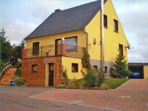 a yellow house with a balcony on a street at Apartment Kenz-Küstrow in Barth