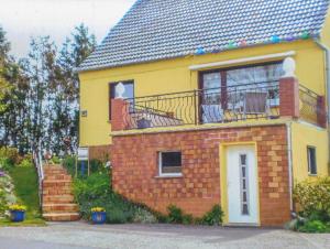 ein gelbes Haus mit einem Balkon und einer Treppe in der Unterkunft Ferienwohnung in Kenz-Küstrow in Barth
