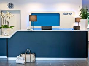 una recepción en una oficina con una pared azul en ibis budget Ulm City en Ulm