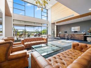 a living room with leather furniture and a glass table at Mercure Kooindah Waters Central Coast in Wyong