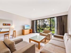 a living room with a couch and a table at Mercure Kooindah Waters Central Coast in Wyong