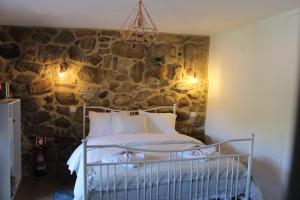 a bed in a room with a stone wall at Suite das Fraguinhas in Sistelo