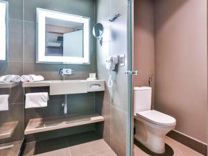 a bathroom with a toilet and a sink and a mirror at Novotel Sorocaba in Sorocaba