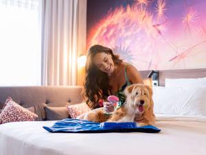 a woman is sitting on a bed with a dog at Novotel Sorocaba in Sorocaba